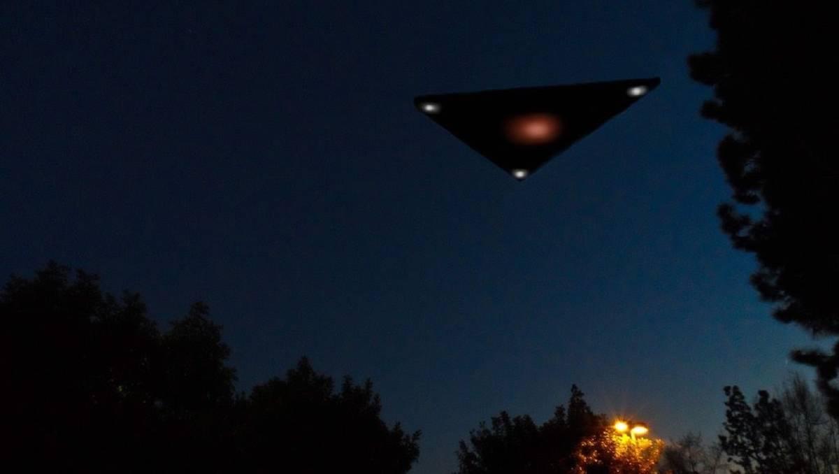 An illustration of a black triangle UFO flying over the treetops at night.