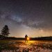 Figure holding a lantern with Milky Way galaxy in background.