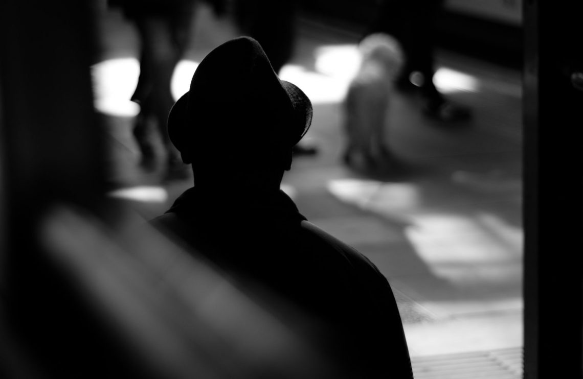 Silhouette of man standing in the train station watching people.