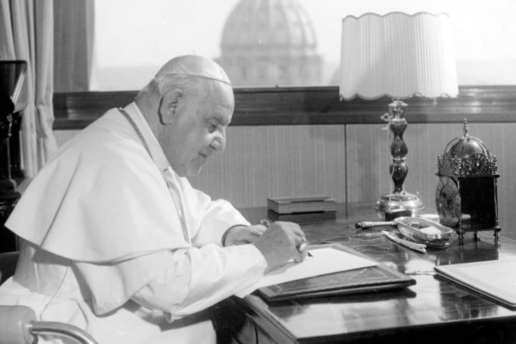 Pope John XXIII at desk writing.