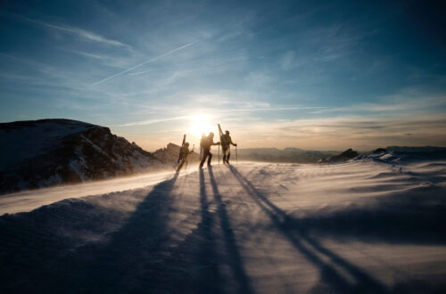 Three people walking on snow.
