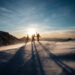 Three people walking on snow.