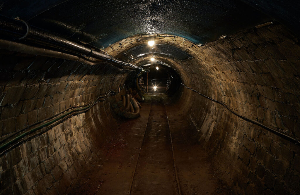 Dark mining tunnel with a light at the end of it.