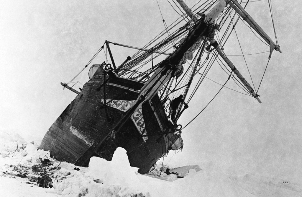 A ship is titled on its side, stuck in a sea of ice.