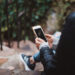 Person holding white smartphone sitting on stairs.