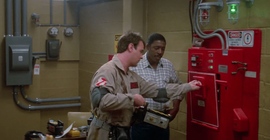 One Ghostbuster observes as another opens an ecto-containment unit.