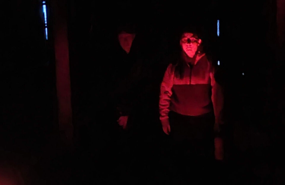 A ghostly apparition appears behind a paranormal investigator.
